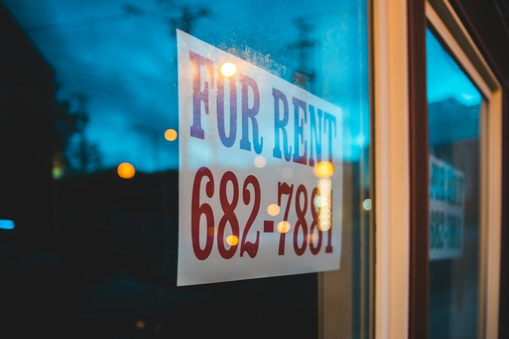 For Rent sign with contact number 682-7881 displayed on a window in the evening glow